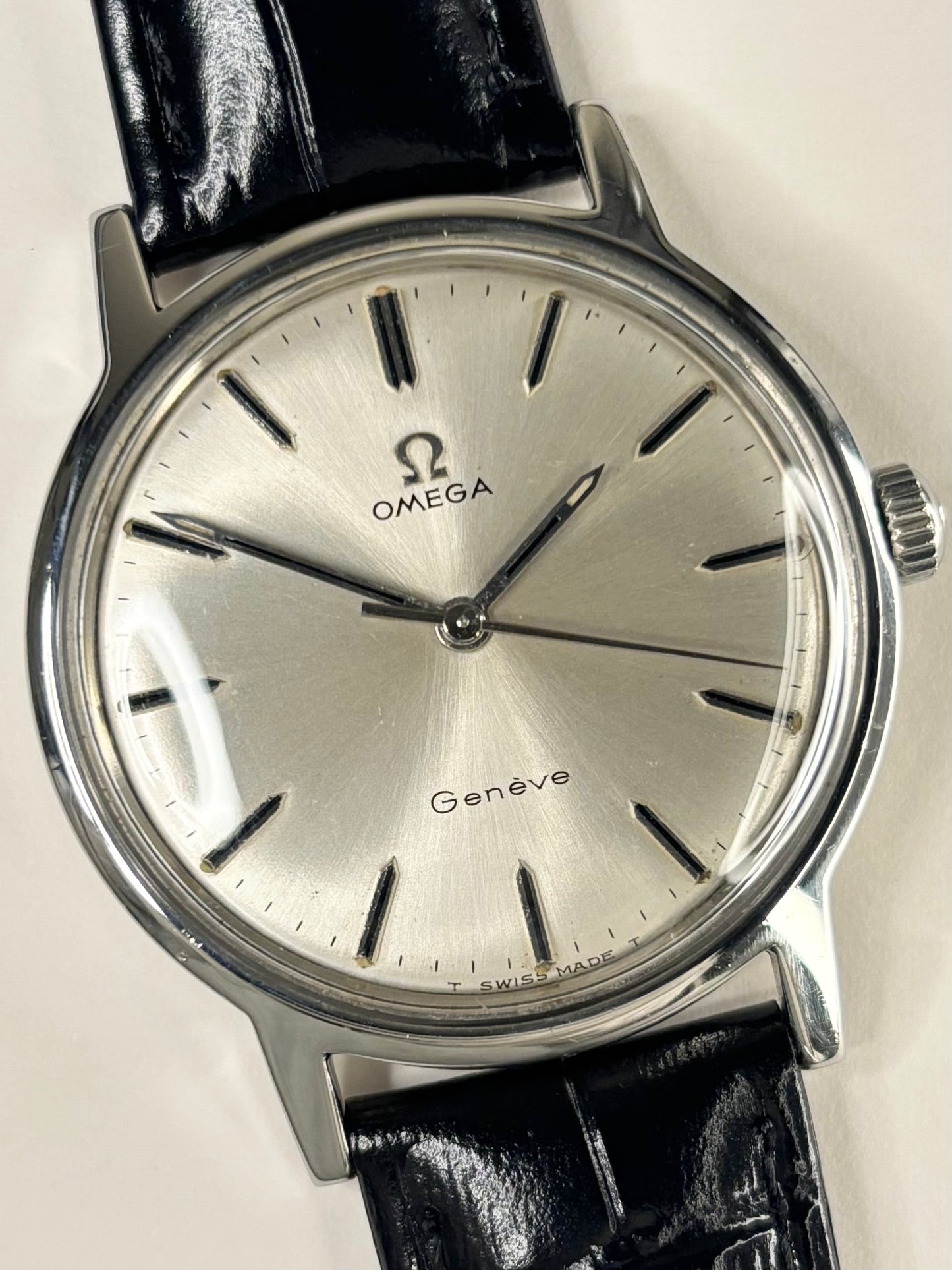 Close-up of Omega Genève vintage manual watch with sunburst dial and stainless steel case, ref. 166.0169