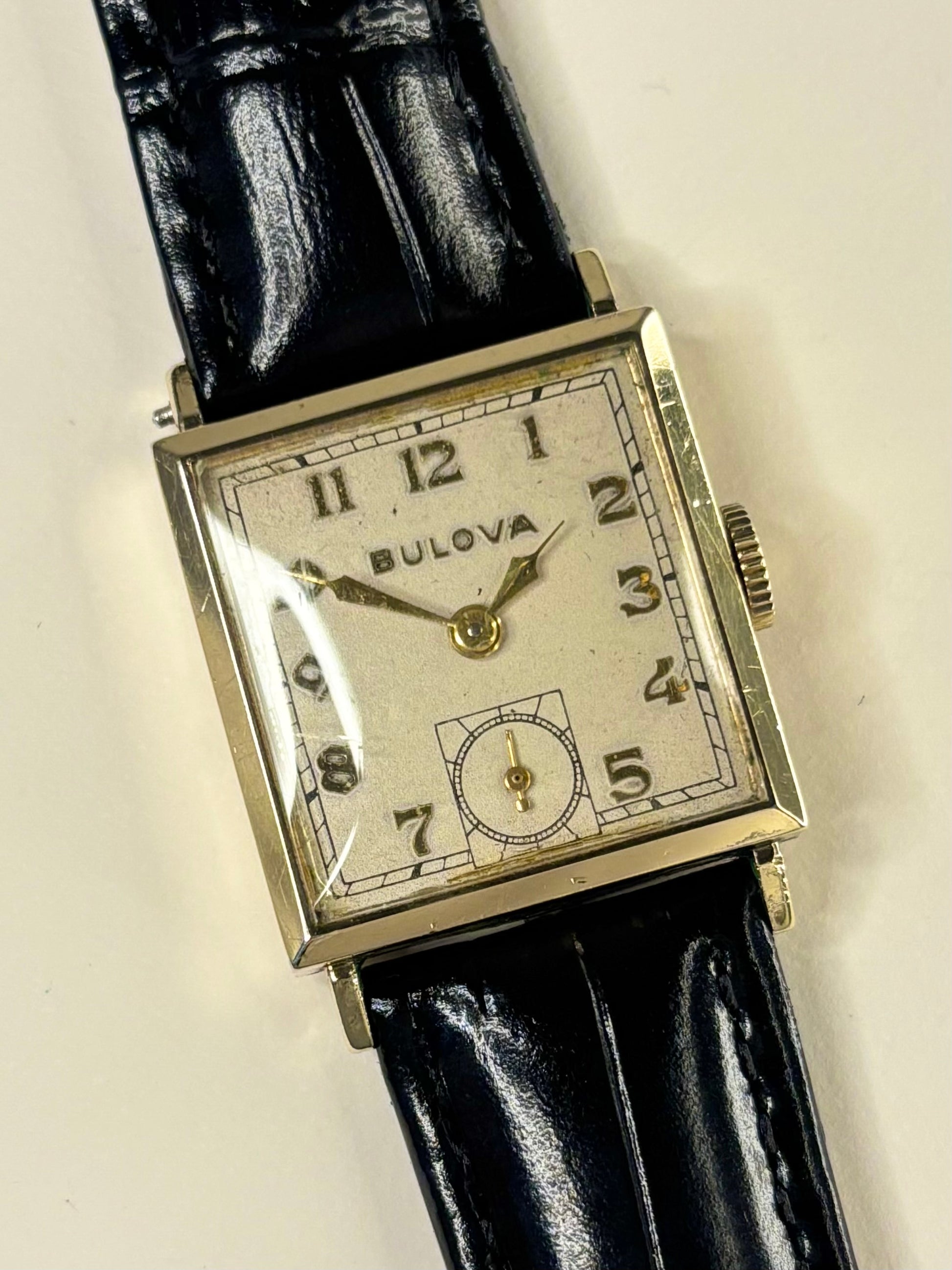Close-up of Bulova 1950s men’s dress watch with white dial and gold filled case