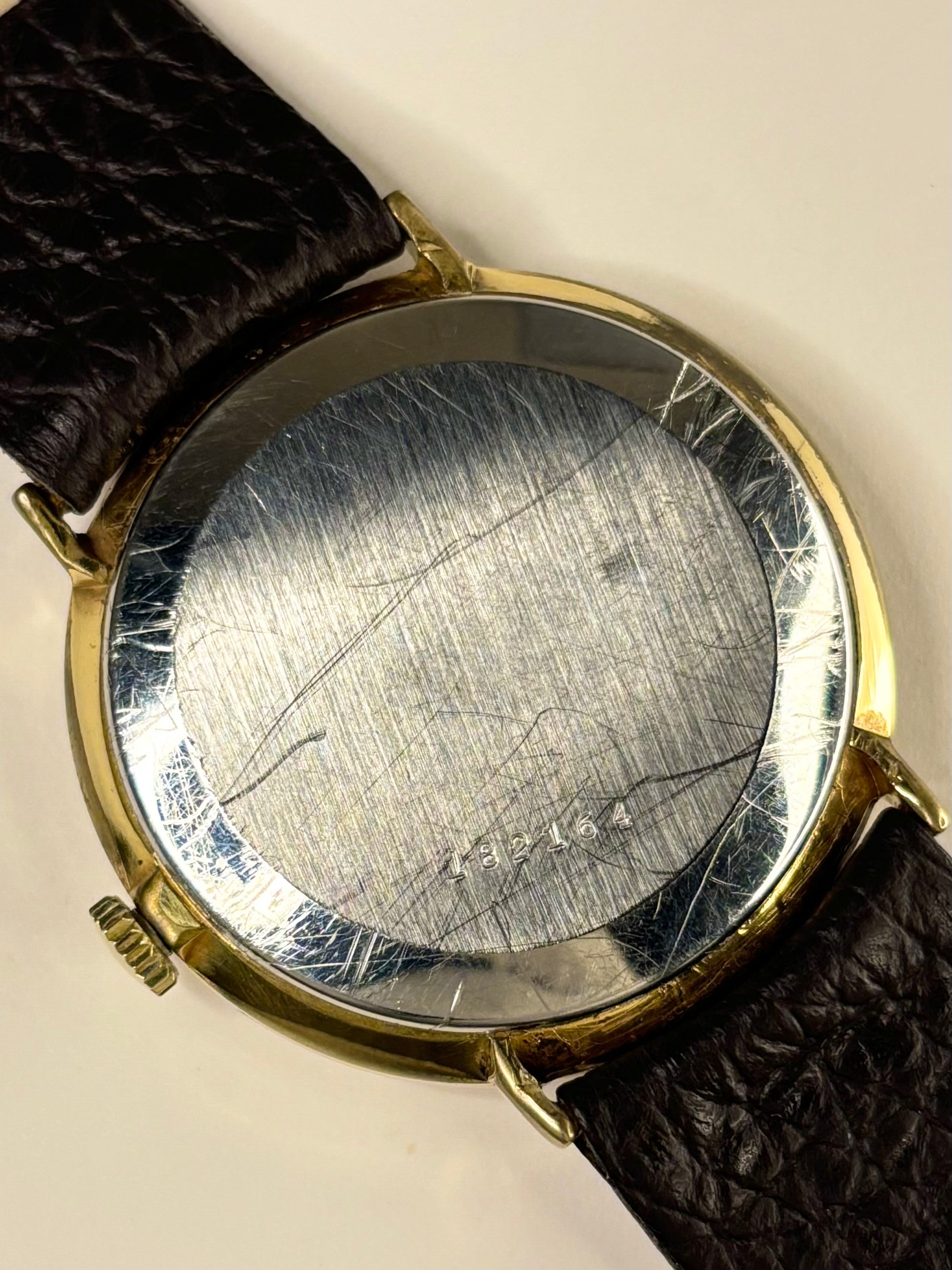 Close-up of Rotary 1990s men’s gold-plated dress watch with white textured dial, manual movement caseback