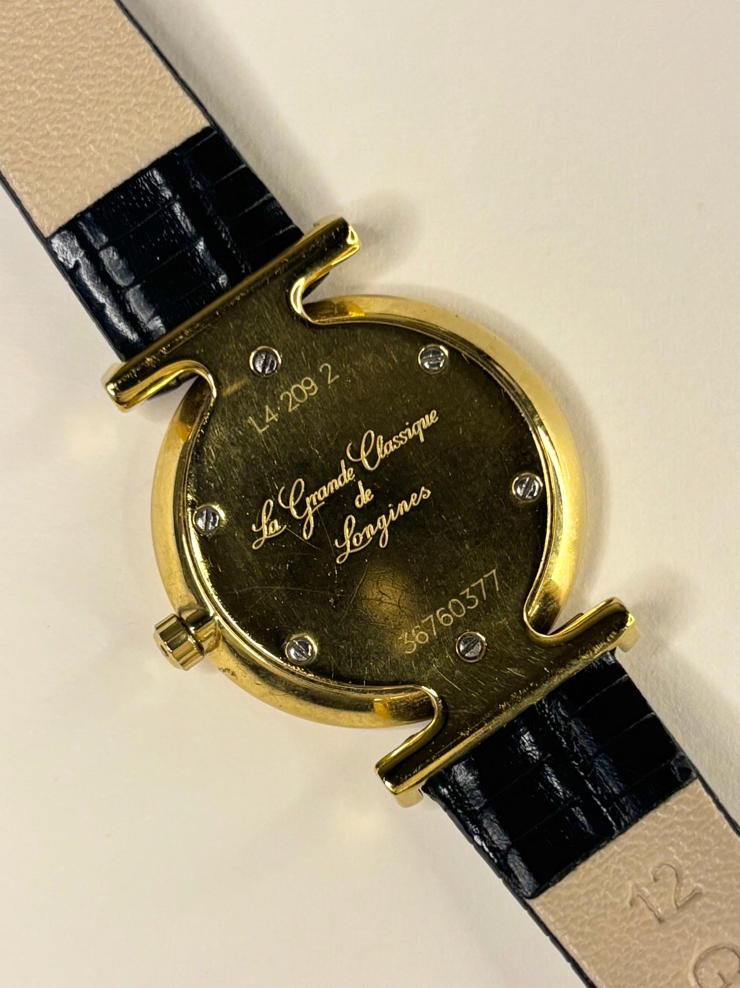 Detailed view of the Longines L4.209.2 caseback ladies timepiece, featuring a bright white dial and gold-plated case, captured as a precise and elegant timekeeper.