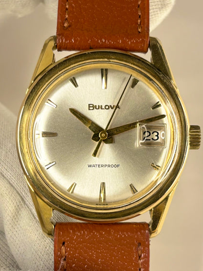 Bulova men’s dress timepiece from the 1970s with white sunburst dial and gold-plated case, presented as a refined vintage timekeeper
