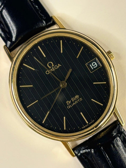 Omega De Ville men’s dress timepiece model 192.0057 with black dial and gold-plated case, powered by calibre 1332 quartz timekeeper