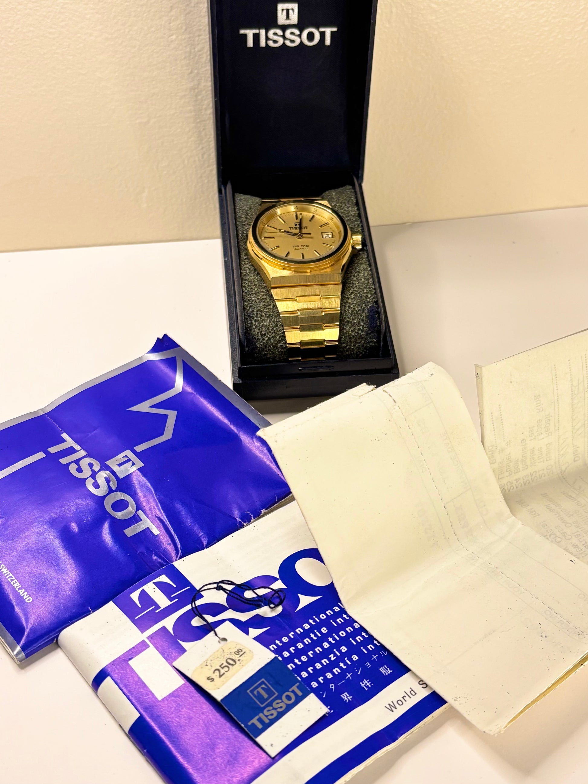 box and papers view of the Tissot PR516 vintage timepiece highlighting its gold-toned dial and gold-plated case as a stylish 1980s timekeeper.